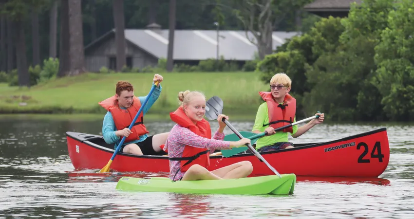 Three kids racing in kayaks
