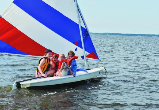 Three girls with counselor on a sailboat
