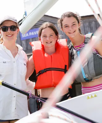 Counselor and two girls setting out to sail