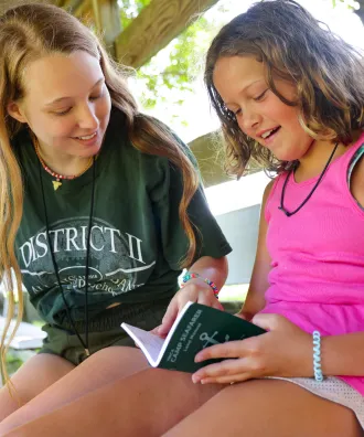 Counselor and camper with green book