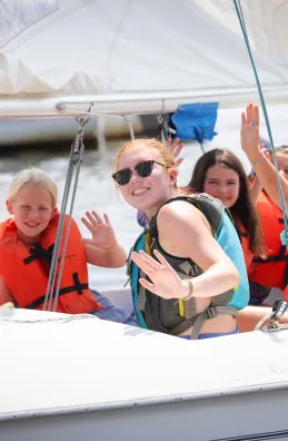 Girls waving at the camera from the sailboat