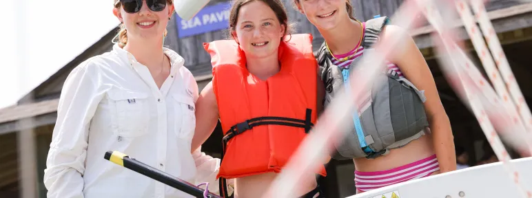 Counselor and two girls setting out to sail
