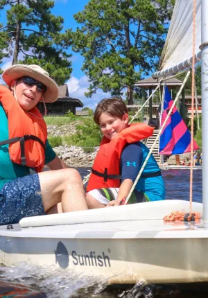 Dad and sun enjoying time on a sailboat during family camp