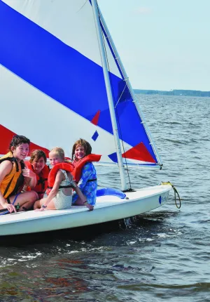 Three girls with counselor on a sailboat