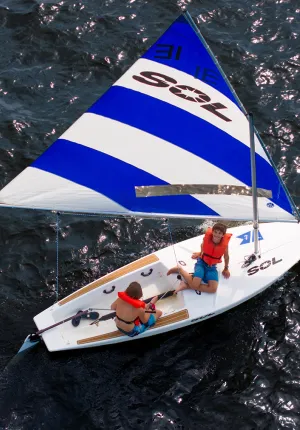 blue and white sailboat on the water with two boys