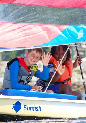 two boys waving from a sailboat