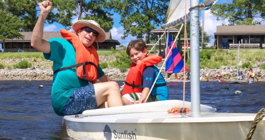 Dad and sun enjoying time on a sailboat during family camp