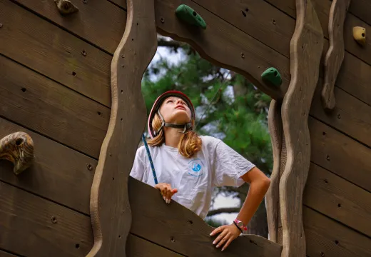 Girl looking through opening on climbing wall