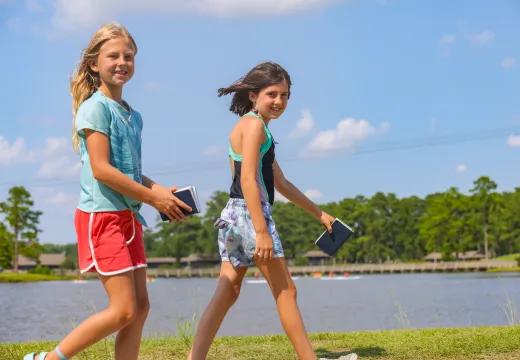 Two girls walking with blue books