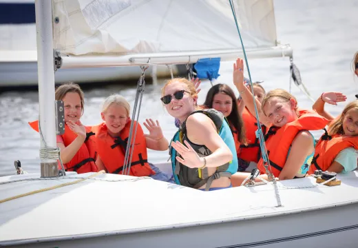 Girls waving at the camera from the sailboat