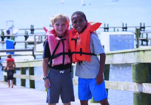 Two friends in life jackets standing by the pier