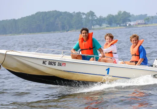 Two campers and a counselor on a motorboat